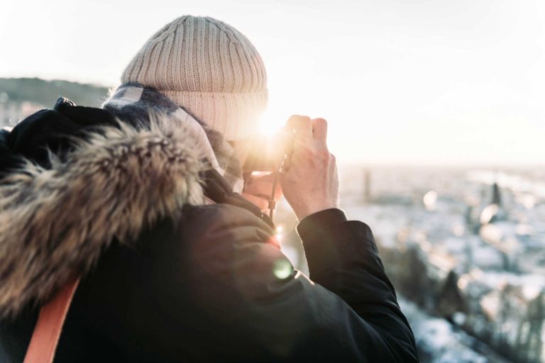 Fotograf im Winterlicht mit Mütze und Kamera, Blick über verschneite Landschaft im Odenwald – stimmungsvolle Aufnahme