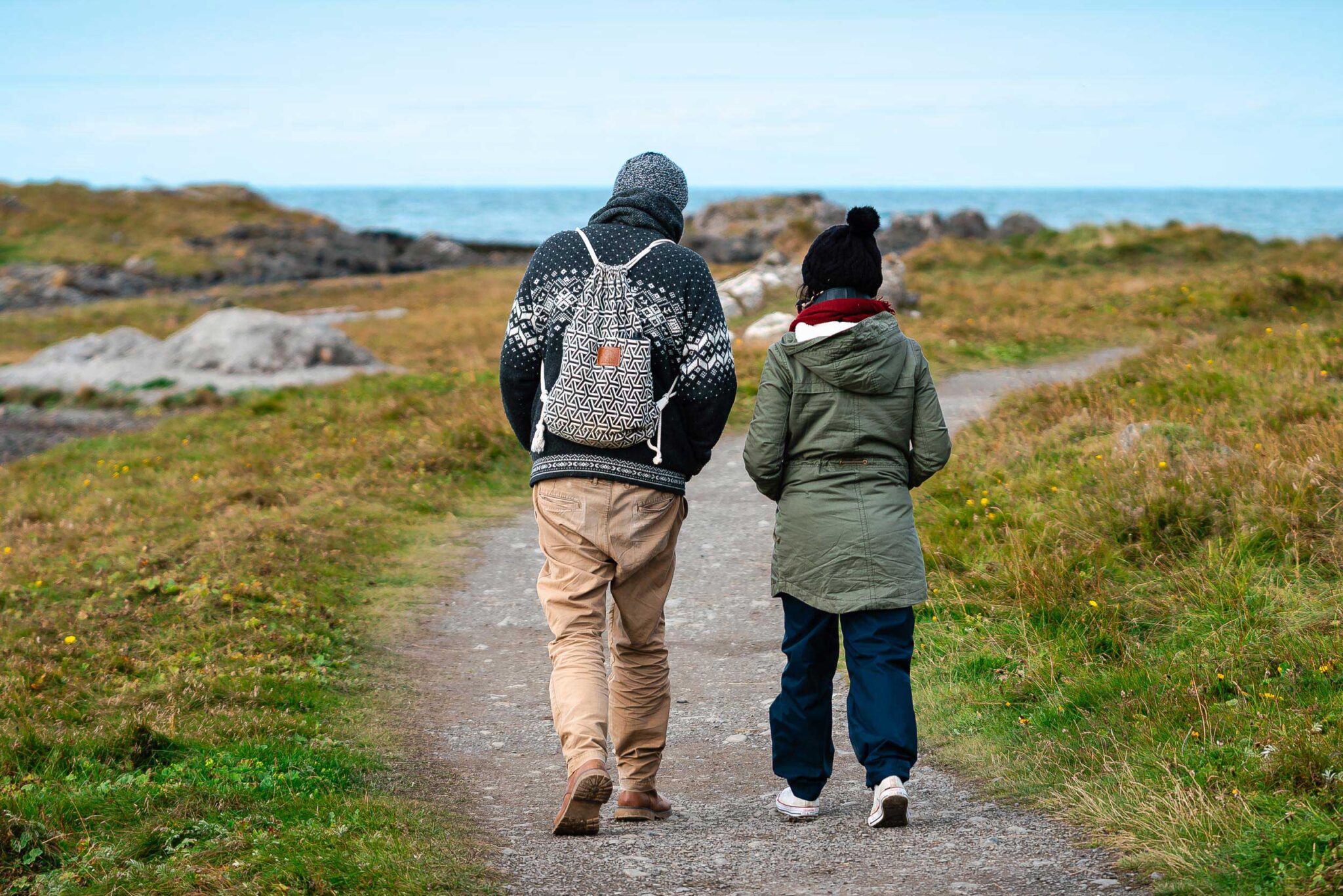 Zwei Personen spazieren auf einem Küstenpfad in Islands weiter Natur mit Blick auf das Meer