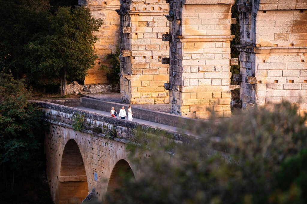 Menschen spazieren bei Sonnenuntergang über die römische Brücke Pont du Gard in Südfrankreich