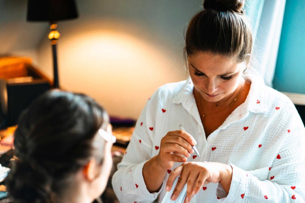 Visagistin schminkt Braut beim Getting Ready in sanftem Licht, detailreiche Hochzeitsfotografie voller Ruhe und Emotion